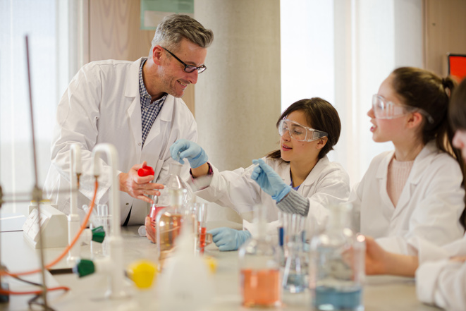 Männlicher Lehrer und Schüler führen wissenschaftliche Experimente im Laborraum durch 