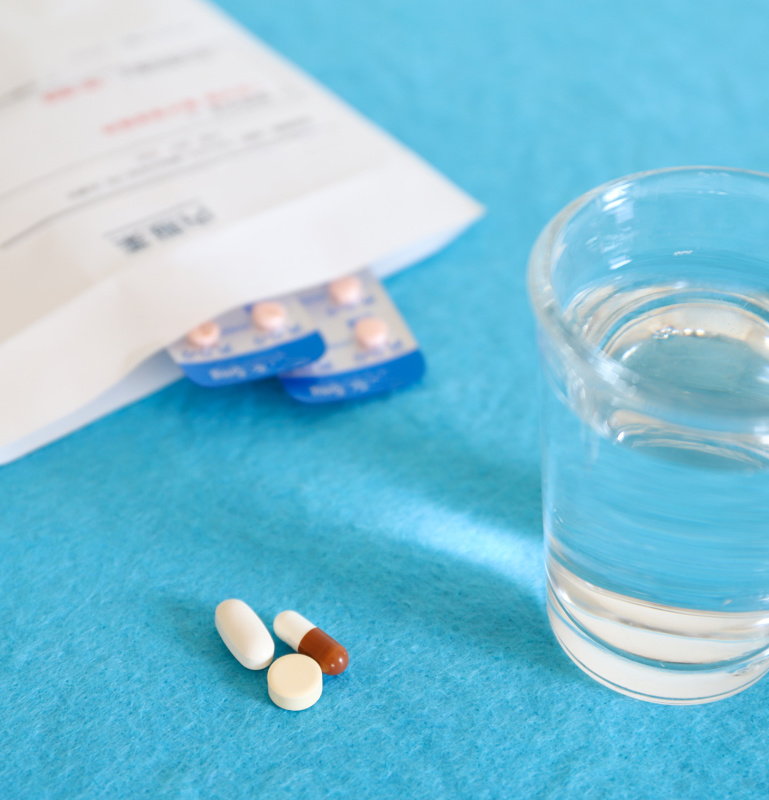 Medikamenten und Wasserglas auf blauer Fläche