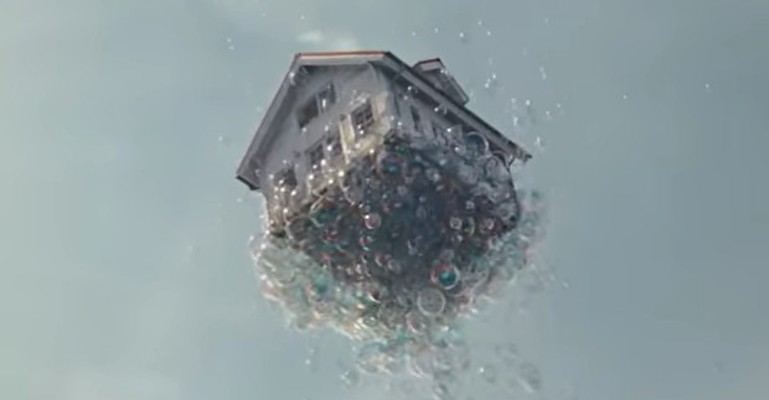 Ein Haus wird von vielen Seifenblasen in den Himmel gehoben.